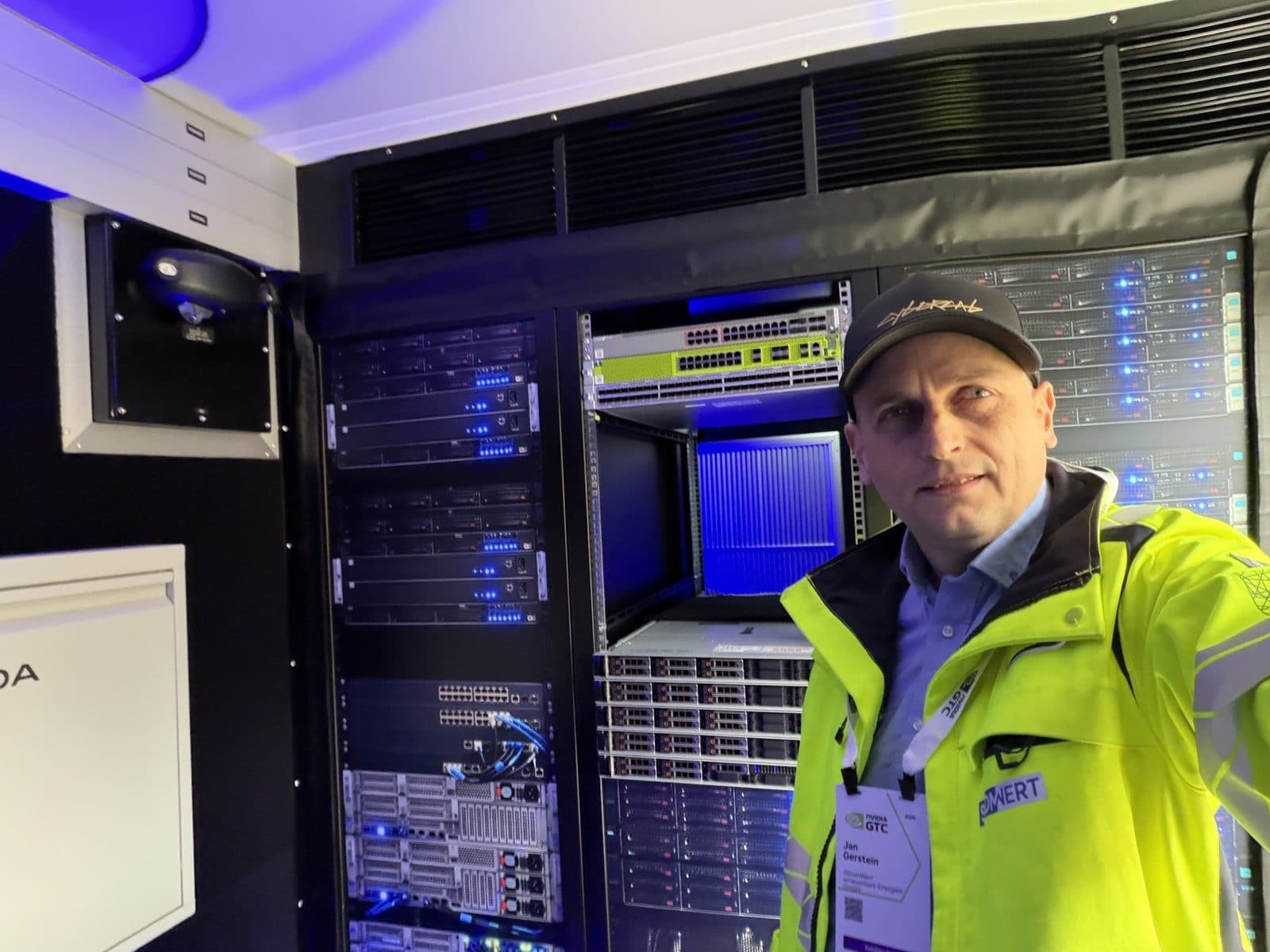 Jan Gerstein in StromWert-Jacke mit Messe-Badge im Galleon-Container, hinter ihm Server-Racks