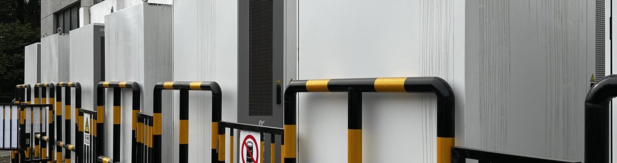 Battery cabinets of a storage park in operation, behind an outdoor barrier